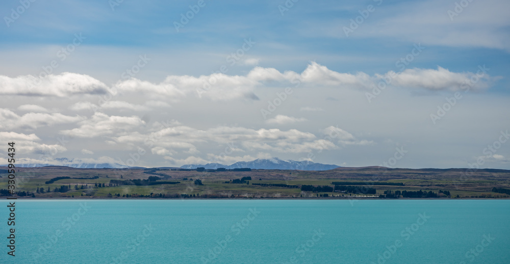 Beautiful view of the bluish Pukaki Lake with snowy Mount Cook in the background, New Zealand