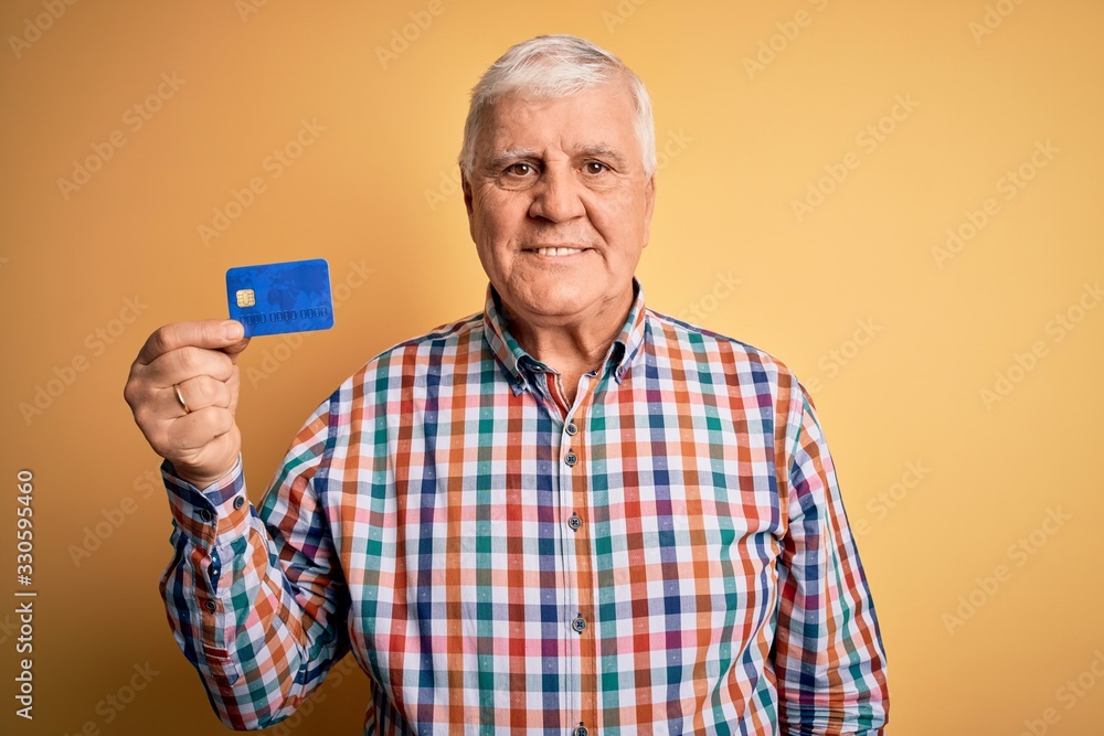 Senior handsome hoary customer man holding credit card to finance payment with a happy face standing and smiling with a confident smile showing teeth Senior handsome hoary customer man holding credit card to finance payment with a happy face standing and smiling with a confident smile showing teeth