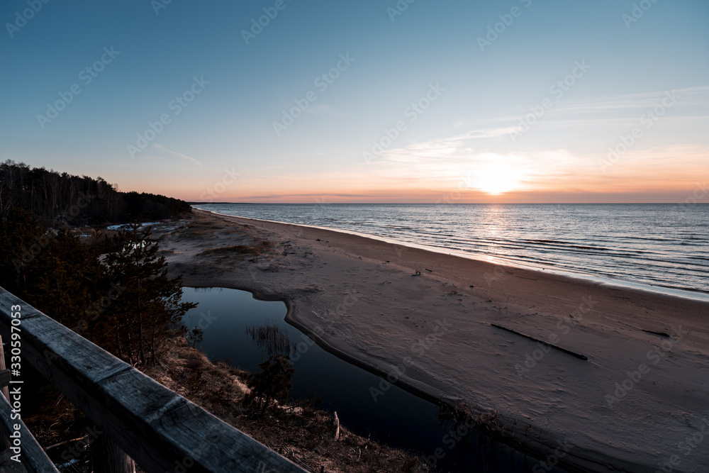 Sunset at Saulkrasti white dune. View from wooden walkpath over sea, small river and sky