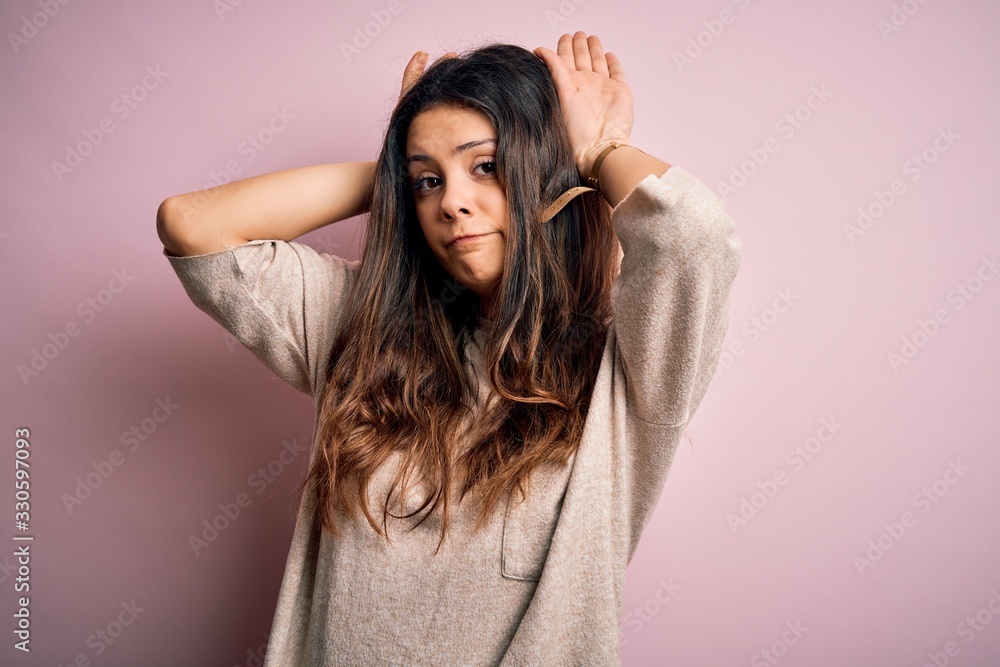 Young beautiful brunette woman wearing casual sweater standing over pink background Doing bunny ears gesture with hands palms looking cynical and skeptical. Easter rabbit concept. Young beautiful brunette woman wearing casual sweater standing over pink background Doing bunny ears gesture with hands palms looking cynical and skeptical. Easter rabbit concept.