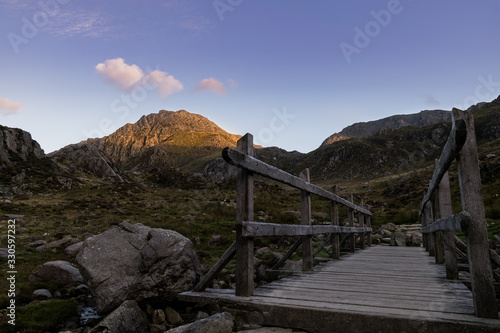 Wooden bridge leading to mountain in Wales at sunset