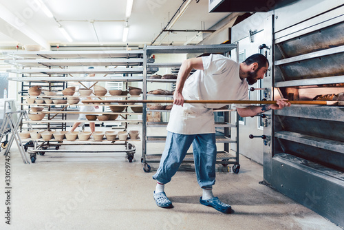 Fototapeta Baker checking bread in the baker oven