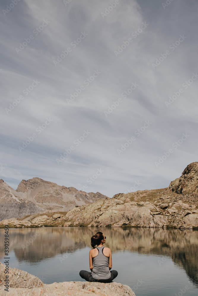 Femme assise au bord d'un lac après une randonnée