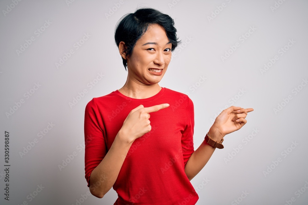 Young beautiful asian girl wearing casual red t-shirt standing over isolated white background Pointing aside worried and nervous with both hands, concerned and surprised expression Young beautiful asian girl wearing casual red t-shirt standing over isolated white background Pointing aside worried and nervous with both hands, concerned and surprised expression