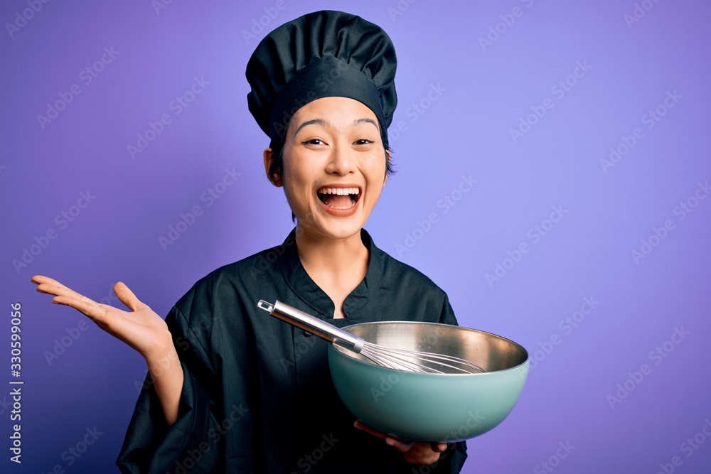 Young beautiful chinese chef woman wearing cooker uniform and hat using bowl and whisk very happy and excited, winner expression celebrating victory screaming with big smile and raised hands Young beautiful chinese chef woman wearing cooker uniform and hat using bowl and whisk very happy and excited, winner expression celebrating victory screaming with big smile and raised hands