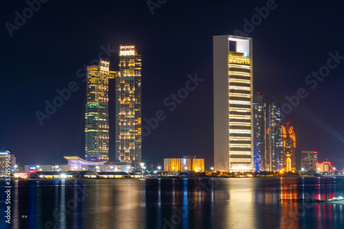 Night view of Abu Dhabi modern skyscrapers panorama. Luxury lifestyle hotels and business of United Arab Emirates.