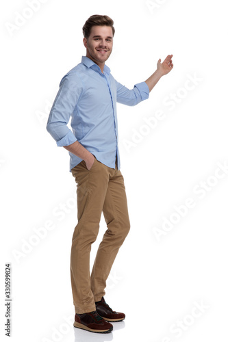 Happy casual man presenting and smiling with hand in pocket