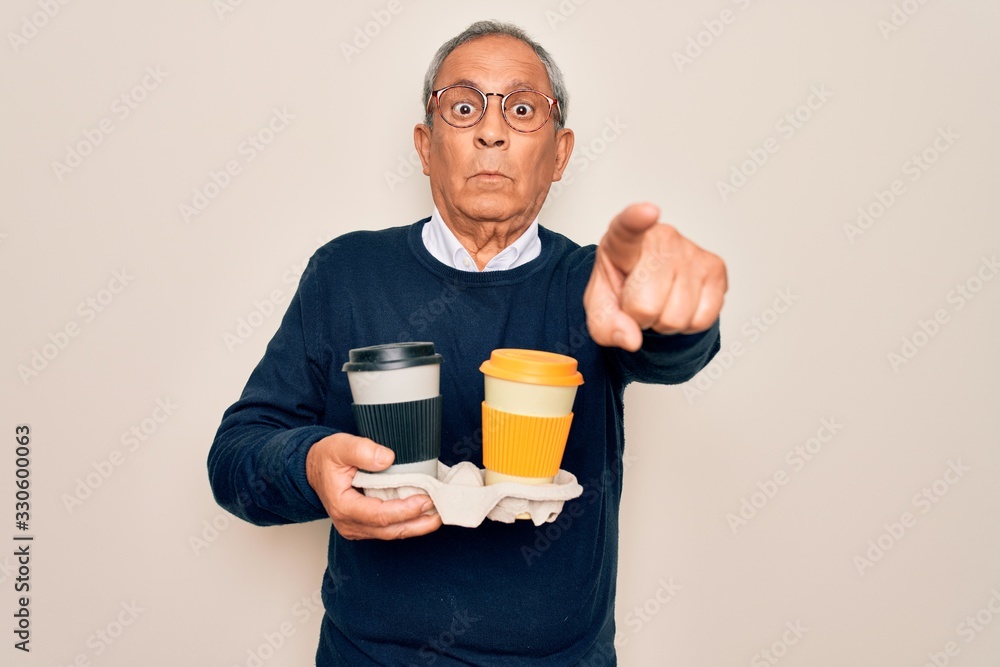 Senior handsome hoary man holding tray with takeaway cups of coffee over white background pointing with finger to the camera and to you, hand sign, positive and confident gesture from the front Senior handsome hoary man holding tray with takeaway cups of coffee over white background pointing with finger to the camera and to you, hand sign, positive and confident gesture from the front