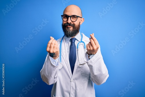 Handsome bald doctor man with beard wearing glasses and stethoscope over blue background doing money gesture with hands, asking for salary payment, millionaire business
