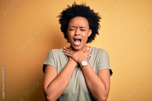 Young beautiful African American afro woman with curly hair wearing casual t-shirt shouting and suffocate because painful strangle. Health problem. Asphyxiate and suicide concept.