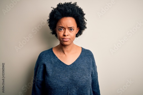 Young beautiful African American afro woman with curly hair wearing casual sweater Relaxed with serious expression on face. Simple and natural looking at the camera. © Krakenimages.com