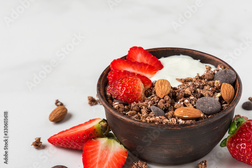 Healthy diet breakfast. bowl of oat chocolate granola with yogurt, fresh strawberries and almonds. close up