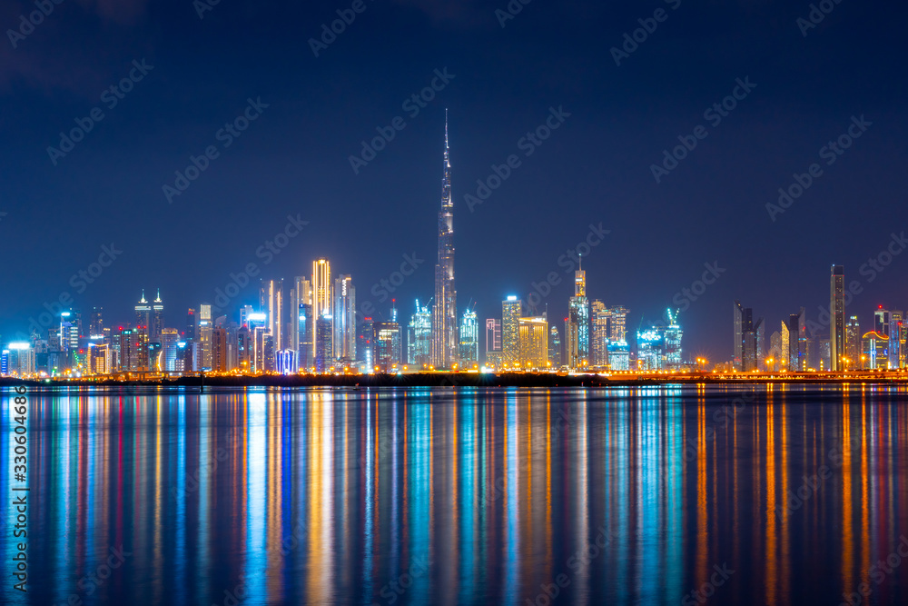 Beautiful view to modern, luxury cityscape panorama from Dubai Creek and colorful reflection of lights in the water canal. Shot at blue hour. 
