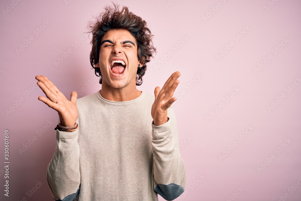 Young handsome man wearing casual t-shirt standing over isolated pink background celebrating mad and crazy for success with arms raised and closed eyes screaming excited. Winner concept Young handsome man wearing casual t-shirt standing over isolated pink background celebrating mad and crazy for success with arms raised and closed eyes screaming excited. Winner concept