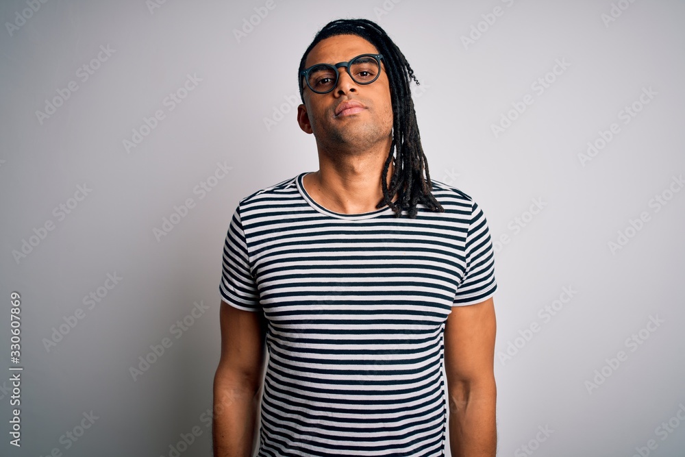Young handsome african american man with dreadlocks wearing striped t-shirt and glasses Relaxed with serious expression on face. Simple and natural looking at the camera. Young handsome african american man with dreadlocks wearing striped t-shirt and glasses Relaxed with serious expression on face. Simple and natural looking at the camera.