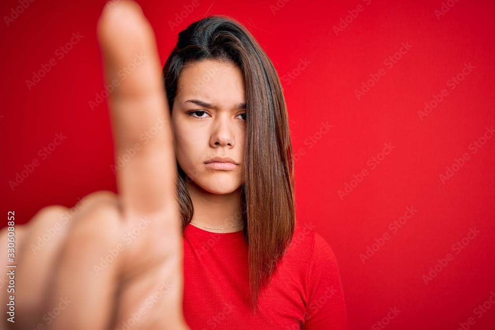 Young beautiful brunette girl wearing casual t-shirt over isolated red background Pointing with finger up and angry expression, showing no gesture Young beautiful brunette girl wearing casual t-shirt over isolated red background Pointing with finger up and angry expression, showing no gesture
