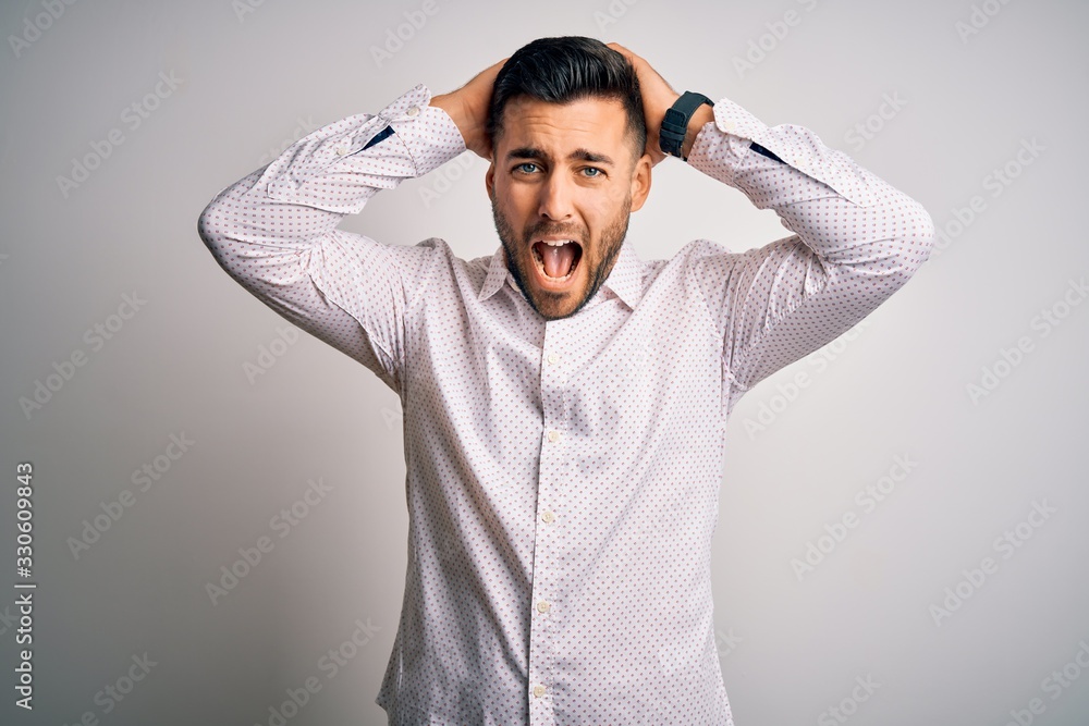 Young handsome man wearing elegant shirt standing over isolated white background Crazy and scared with hands on head, afraid and surprised of shock with open mouth Young handsome man wearing elegant shirt standing over isolated white background Crazy and scared with hands on head, afraid and surprised of shock with open mouth