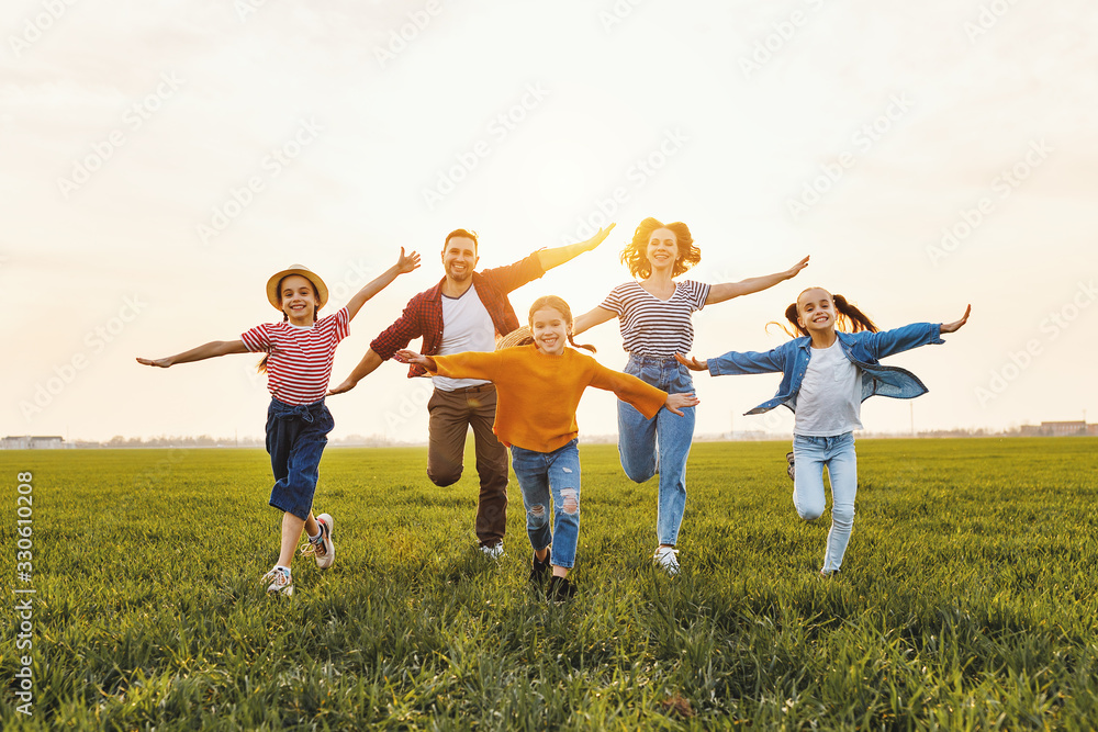 Happy family running in field in summer evening. Happy family running in field in summer evening.