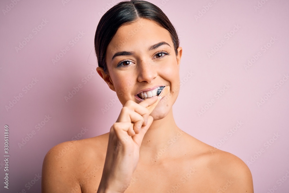Young beautiful brunette woman brushing her teeth using tooth brush and oral paste, cleaning teeth and tongue as healthy health care morning routine Young beautiful brunette woman brushing her teeth using tooth brush and oral paste, cleaning teeth and tongue as healthy health care morning routine