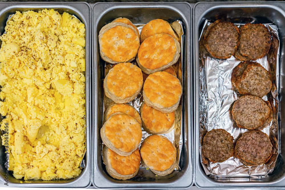 Fresh hot buffet tray flat top view of food scrambled eggs, biscuits and sausages in banquet, wedding, or restaurant inside for morning continental breakfast in hotel motel Fresh hot buffet tray flat top view of food scrambled eggs, biscuits and sausages in banquet, wedding, or restaurant inside for morning continental breakfast in hotel motel