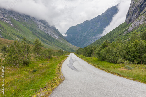The road leading a mysterious gorge surrounded by clouds of the Norwegian mountains, selective focus