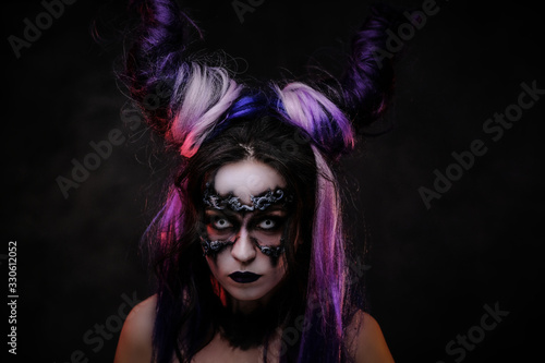 Close up photo of a mystic young girl in a magic creature cosplay, wearing dark banshee make-up and violet horns, looking scary