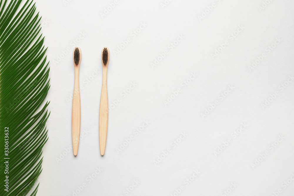 Wooden tooth brushes with palm leaf on white background Wooden tooth brushes with palm leaf on white background