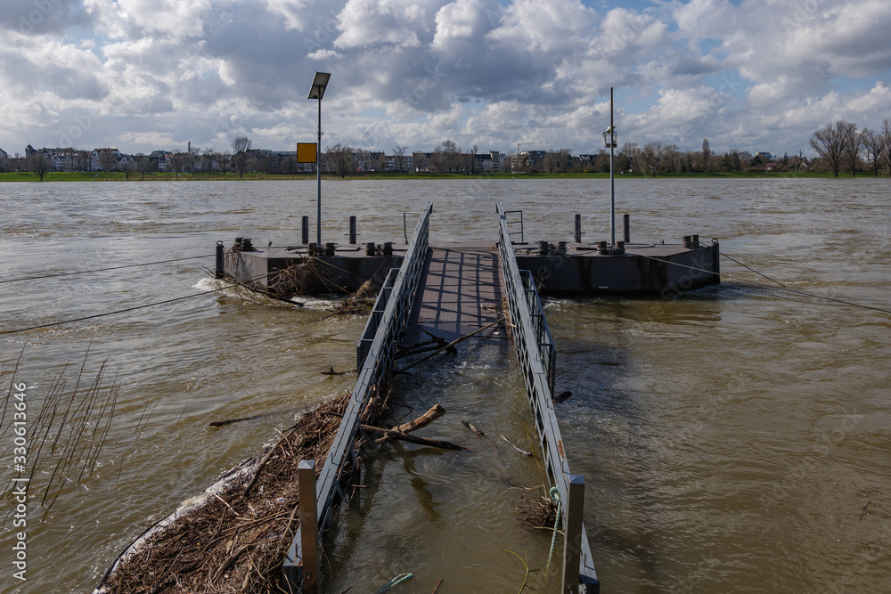 Strong, swift and rapid flow or rough stream current flood over abandon broken damaged rusty steel bridge toward pier, pontoon or buoy over Rhine River and background of riverside and cloudy sky. Strong, swift and rapid flow or rough stream current flood over abandon broken damaged rusty steel bridge toward pier, pontoon or buoy over Rhine River and background of riverside and cloudy sky.