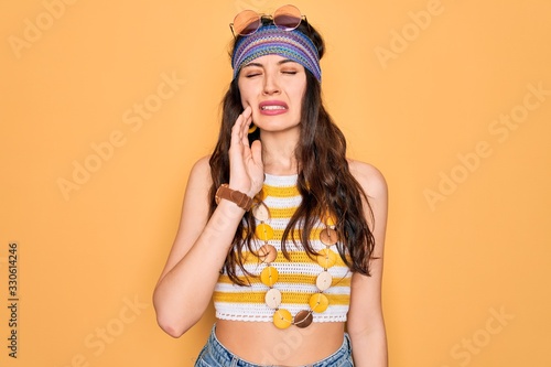 Young beautiful hippie woman with blue eyes wearing accesories and sunnglasses touching mouth with hand with painful expression because of toothache or dental illness on teeth. Dentist photo