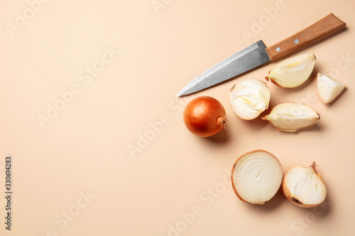 Fresh cut onion and knife on color background