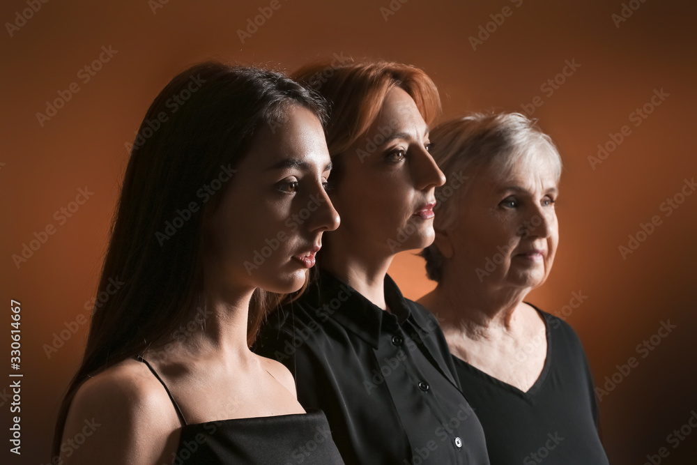 Portrait of mature woman with her adult daughter and mother on dark color background Portrait of mature woman with her adult daughter and mother on dark color background