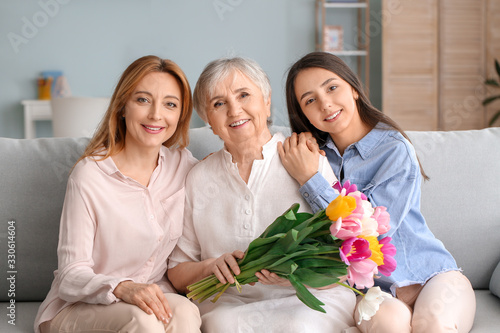 Mature woman with her adult daughter, mother and beautiful flowers at home