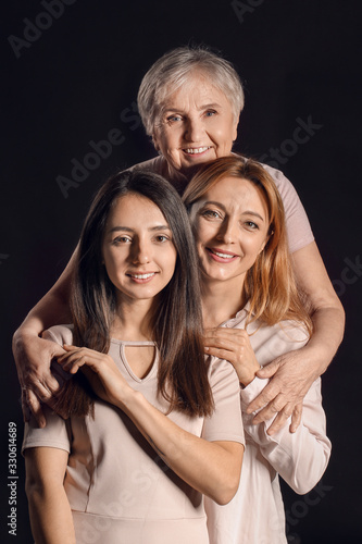 Portrait of mature woman with her adult daughter and mother on dark background
