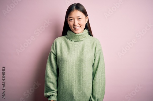 Young beautiful asian woman wearing green winter sweater over pink solated background with a happy and cool smile on face. Lucky person. © Krakenimages.com