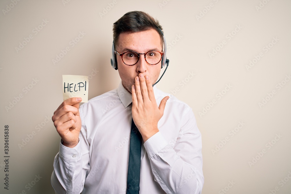 Young call center operator man wearing headset holding paper note with help word cover mouth with hand shocked with shame for mistake, expression of fear, scared in silence, secret concept Young call center operator man wearing headset holding paper note with help word cover mouth with hand shocked with shame for mistake, expression of fear, scared in silence, secret concept