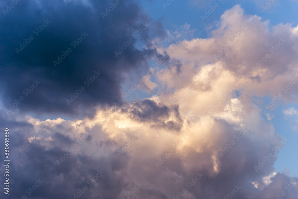 Dramatic storm dark and white cumulus clouds in sunlight on blue sky background texture	