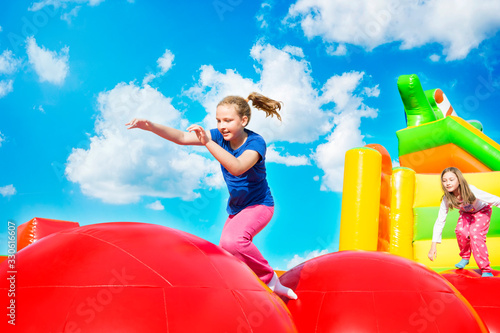 Happy little girls having lots of fun while jumping from ball to ball on an inflate castle Fototapeta