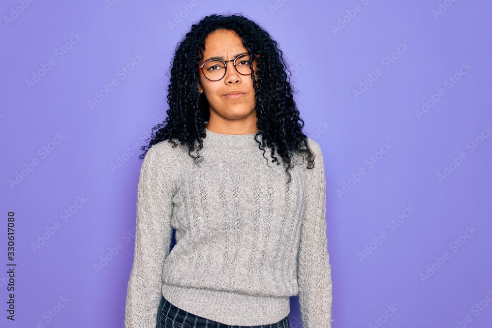 Young african american woman wearing casual sweater and glasses over purple background Relaxed with serious expression on face. Simple and natural looking at the camera. Young african american woman wearing casual sweater and glasses over purple background Relaxed with serious expression on face. Simple and natural looking at the camera.