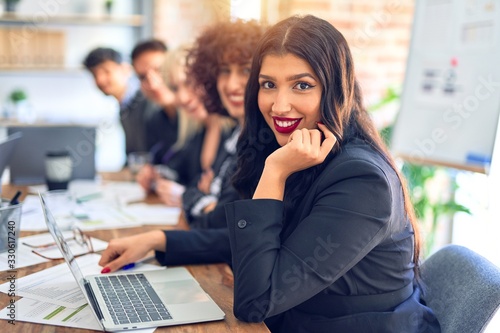 Group of business workers sitting in line with smile on face. Looking at the camera, young beautiful woman smiling at the office