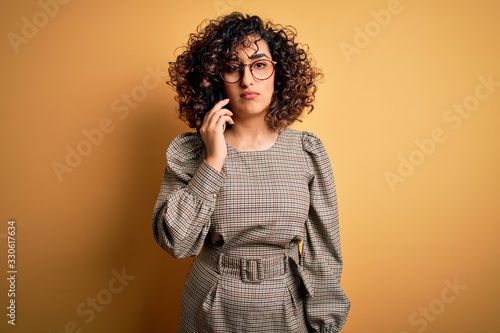 Beautiful arab businesswoman wearing glasses having conversation talking on smartphone with a confident expression on smart face thinking serious © Krakenimages.com