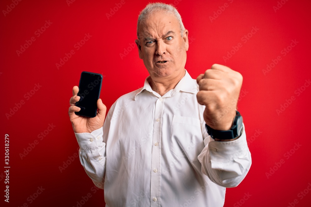 Middle age hoary man holding smartphone showing screen over isolated red background annoyed and frustrated shouting with anger, crazy and yelling with raised hand, anger concept Middle age hoary man holding smartphone showing screen over isolated red background annoyed and frustrated shouting with anger, crazy and yelling with raised hand, anger concept