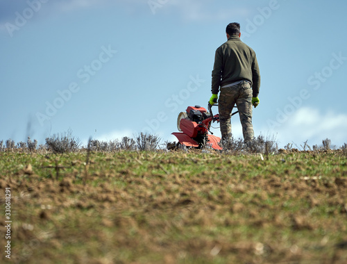 Farmer weeding the field with a tiller photo