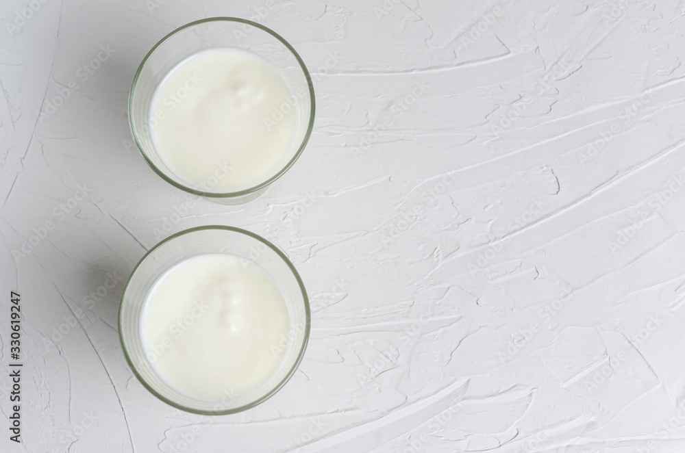 Fototapeta premium Home-made fermented kefir drink on a white background, copy space, place for text. Sour milk drink, sourdough for yeast bacterial fermentation, intestinal health concept. View from above