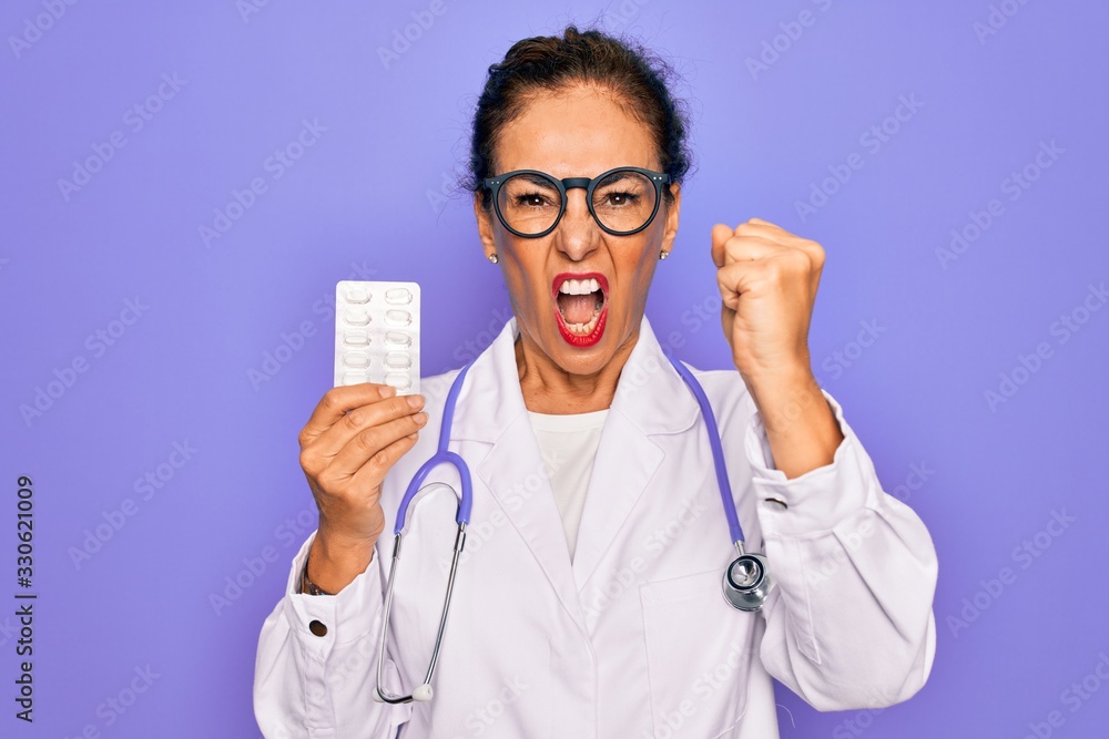 Middle age senior professional doctor woman holding pharmaceutical pills annoyed and frustrated shouting with anger, crazy and yelling with raised hand, anger concept Middle age senior professional doctor woman holding pharmaceutical pills annoyed and frustrated shouting with anger, crazy and yelling with raised hand, anger concept