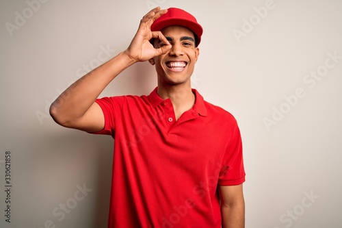 Young handsome african american man wearing casual polo and cap over red background doing ok gesture with hand smiling, eye looking through fingers with happy face.
