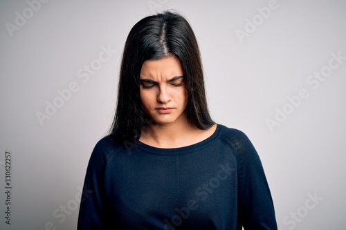 Young beautiful brunette woman wearing casual sweater standing over white background with hand on stomach because indigestion, painful illness feeling unwell. Ache concept. © Krakenimages.com