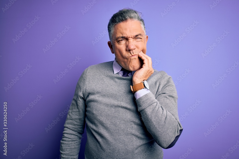 Middle age handsome grey-haired man wearing elegant sweater over purple background touching mouth with hand with painful expression because of toothache or dental illness on teeth. Dentist Middle age handsome grey-haired man wearing elegant sweater over purple background touching mouth with hand with painful expression because of toothache or dental illness on teeth. Dentist