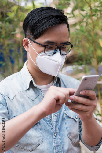 Asian men wearing medical masks use mobile phones on the streets of cities photo