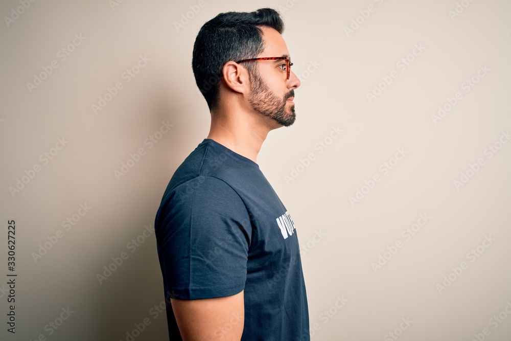 Handsome man with beard wearing t-shirt with volunteer message over white background looking to side, relax profile pose with natural face and confident smile. Handsome man with beard wearing t-shirt with volunteer message over white background looking to side, relax profile pose with natural face and confident smile.