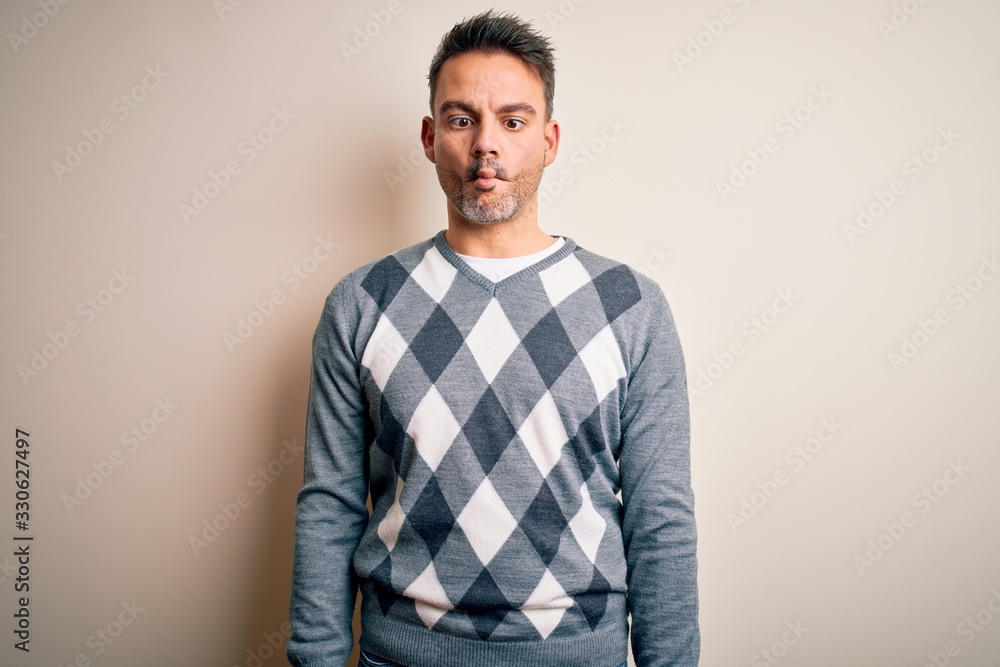 Young handsome man wearing casual sweater standing over isolated white background making fish face with lips, crazy and comical gesture. Funny expression. Young handsome man wearing casual sweater standing over isolated white background making fish face with lips, crazy and comical gesture. Funny expression.
